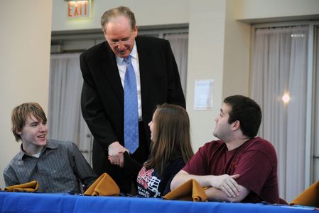 Rockefeller stands behind three students and talks to them